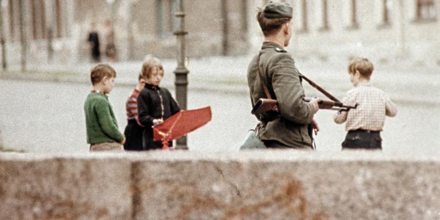 Armed guard and playing children at the Berlin Wall