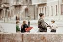 Armed guard and playing children at the Berlin Wall